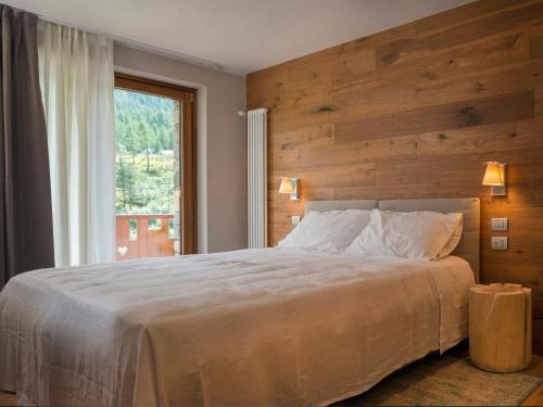 una camera da letto con un grande letto con una grande finestra di 3 Chalets Aparthotel a Breuil-Cervinia