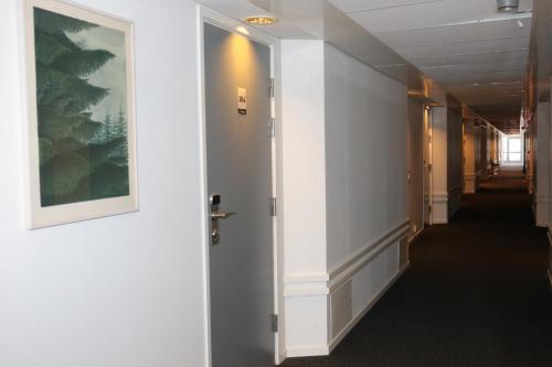 a hallway with a door and a painting on the wall at Hotell Norrort in Vallentuna
