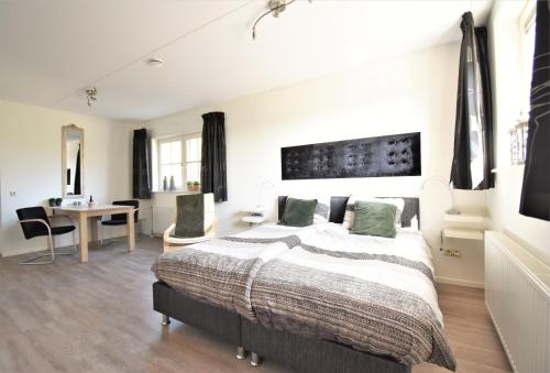a bedroom with a bed and a desk and a table at De Beddestee in Ruinen