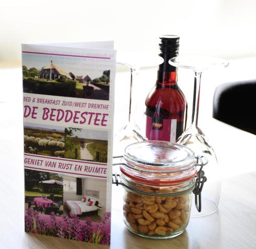 a bottle of wine next to a book and a jar of beans at De Beddestee in Ruinen