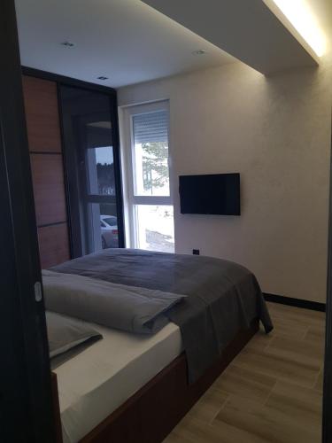 a bedroom with a bed and a television on the wall at Divcibare Golden Luxx Apartman in Divčibare