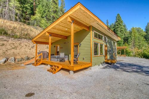 a small green cabin with a large deck in the woods at Perrydise in Leavenworth
