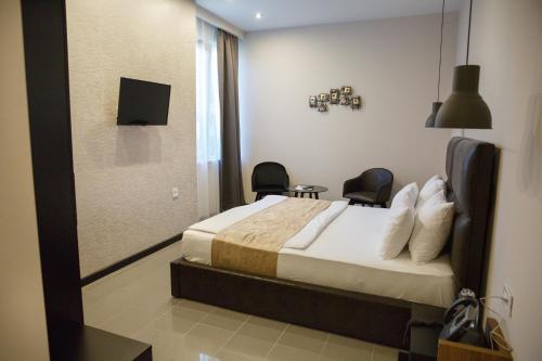 a bedroom with a bed with two chairs and a mirror at Hotel Crystal Light in Niš