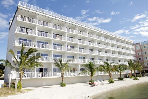 um grande hotel branco na praia com palmeiras em Princess Bayside Beach Hotel em Ocean City