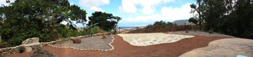 a garden with a bed and rocks and trees at Casa el Porte in Tegueste