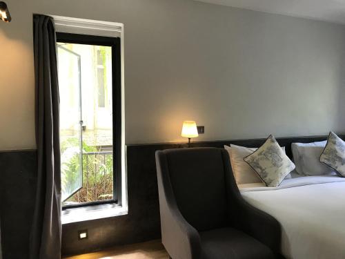 Un dormitorio con una cama y una silla y una ventana. en Hotel Noir, en Chiang Mai