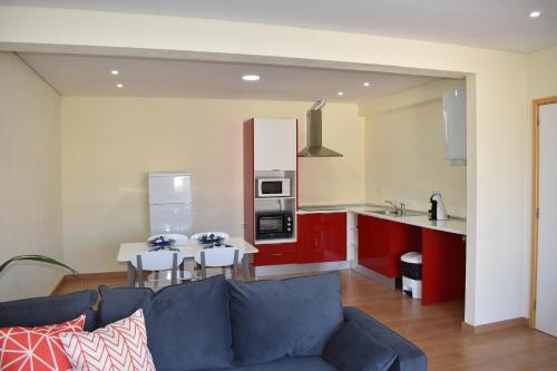 a living room with a blue couch and a kitchen at Varanda do jardim in Belmonte