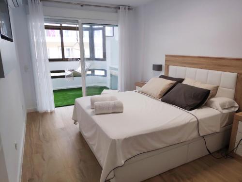 a white bedroom with a large bed and a window at Apartamento IMPERIO 1 - Marbella centro in Marbella