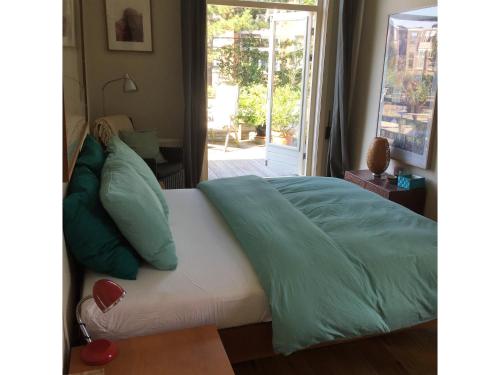 een bed met groene lakens en kussens in een slaapkamer bij Bed & Breakfast Leonie in Den Haag