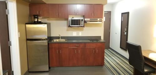 a kitchen with wooden cabinets and a stainless steel refrigerator at Super 8 by Wyndham Brandon MB in Brandon