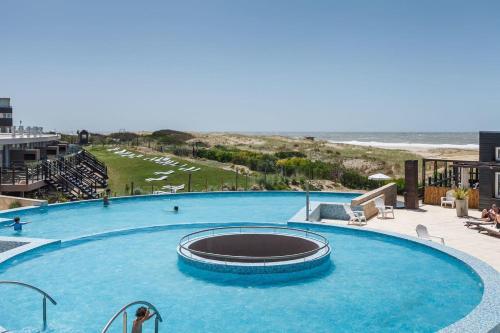 a large swimming pool with the beach in the background at Linda Bay Premium Resort in Mar de las Pampas