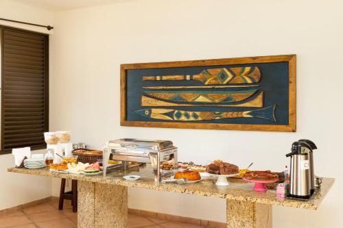 a table with food on it with a picture on the wall at Pousada Kia Ora Bombinhas in Bombinhas