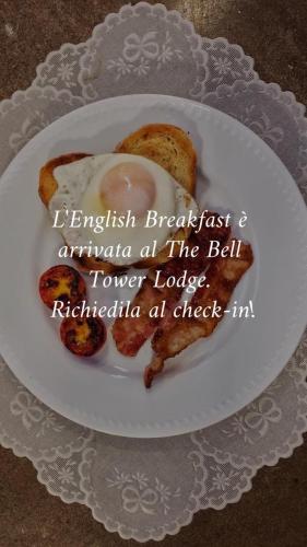 a white plate with an egg and bread on it at The Bell Tower Lodge in Palidoro