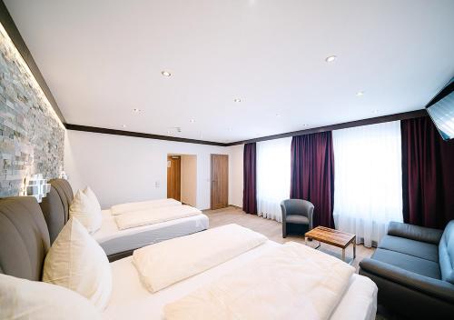 a hotel room with two beds and a couch at Central City Hotel in Füssen