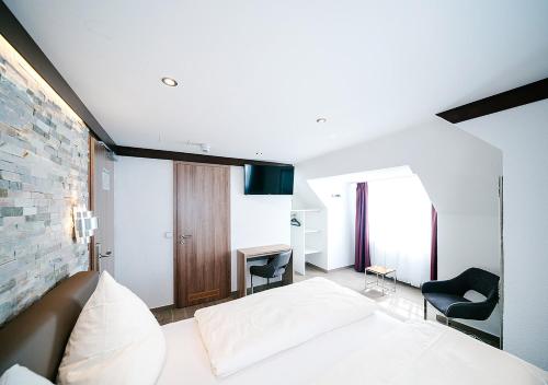 a bedroom with a white bed and a chair at Central City Hotel in Füssen