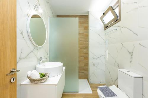 a white bathroom with a sink and a mirror at Villa Anemolia in Lefkogeia
