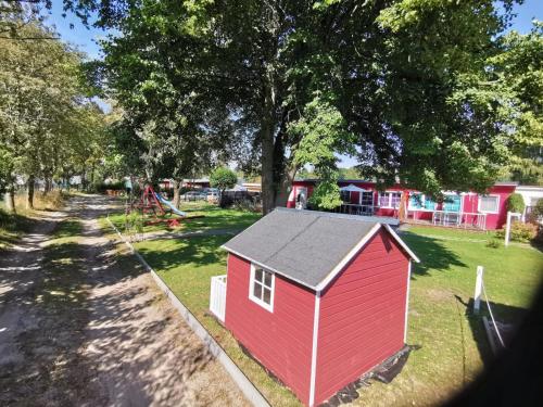 a red shed in a yard with a playground at Bungalows am Grimnitzsee in Joachimsthal