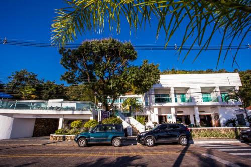 two cars parked in a parking lot in front of a building at Hotel Ilhabela in Ilhabela