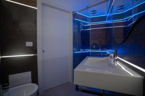 a bathroom with a sink and a toilet with blue lights at La Lupa in Matera