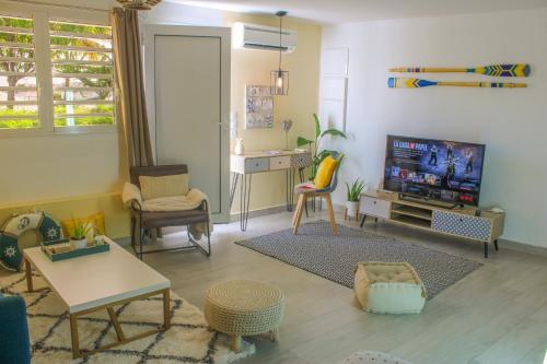 a living room with a tv and a table and chairs at COLIBRIS PARADISE LA MARINA in Le Gosier