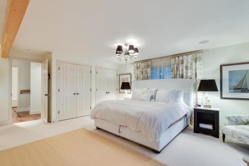 a white bedroom with a large bed and a chandelier at South Hampton House in Tolovana Park