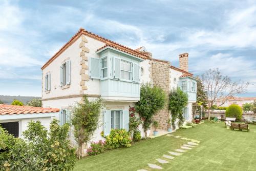 a large white house with a yard with grass at Deniz Kabugu Hotel in Alacati