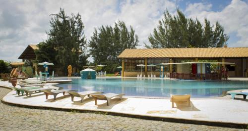 a large swimming pool with chairs and a building at Pousada Chácara Lago Seco in Camocim