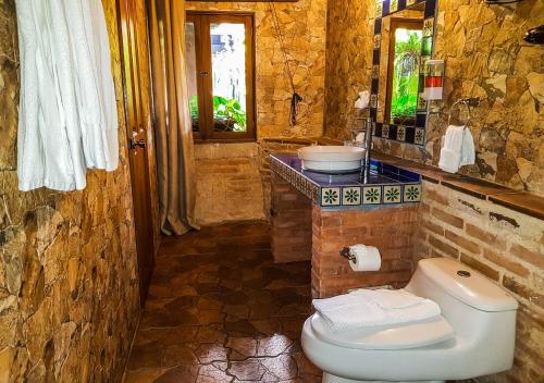 a stone bathroom with a toilet and a sink at Hotel Eterna Primavera Antigua in Antigua Guatemala