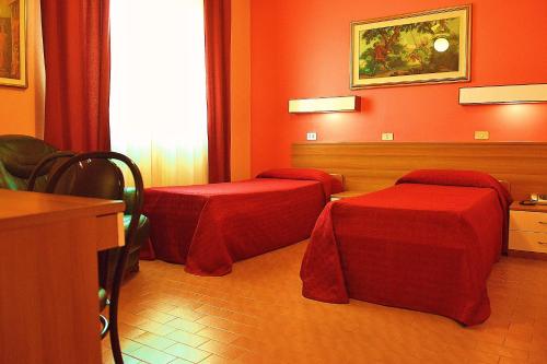 two beds in a room with red walls at Hotel Rosy in Arluno