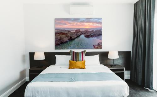 a bedroom with a bed with a painting on the wall at Coniston Hotel Wollongong in Wollongong