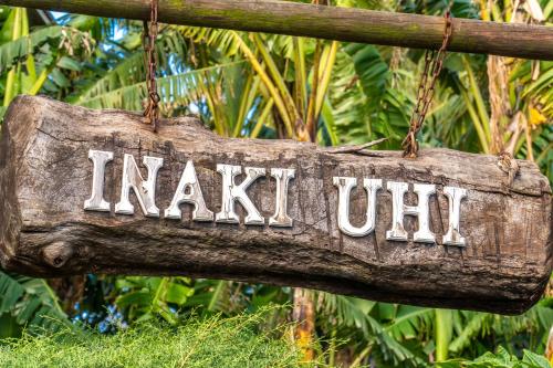 a wooden sign hanging from a tree branch at Inaki Uhi Hotel in Hanga Roa