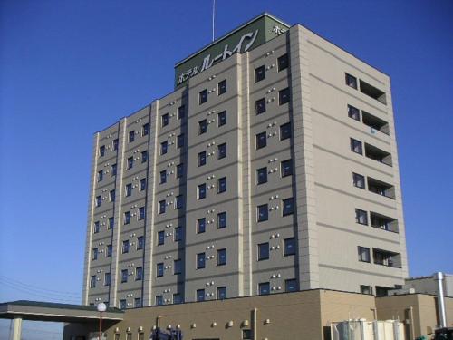 a tall building with a sign on the top of it at Hotel Route-Inn Nagaoka Inter in Nagaoka