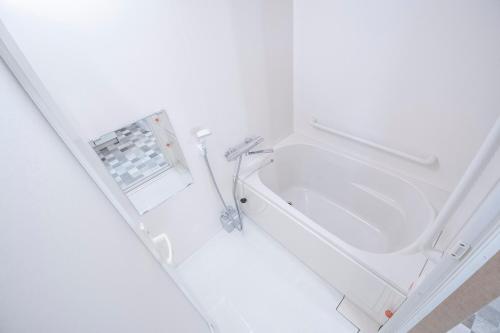 a white bathroom with a sink and a bath tub at UCHI Living Stay Otaru Suitengu in Otaru