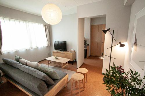 a living room with a couch and a tv at UCHI Living Stay Otaru Suitengu in Otaru