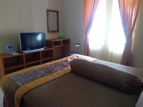 a bedroom with a bed and a tv and a window at Villagio Hotel in Pameungpeuk