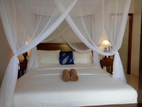 a bed with two pairs of shoes sitting on it at Suryadina Guest House in Ubud