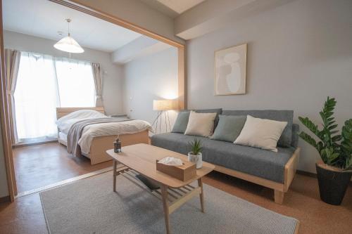 a living room with a couch and a bed at UCHI Living Stay Otaru Suitengu in Otaru