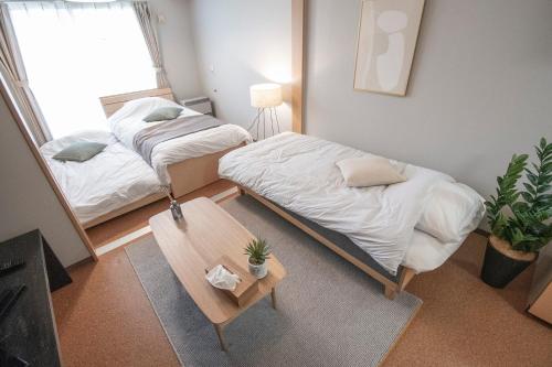 a room with two beds and a table and a window at UCHI Living Stay Otaru Suitengu in Otaru