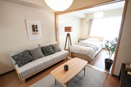 a living room with a couch and a bed at UCHI Living Stay Otaru Suitengu in Otaru
