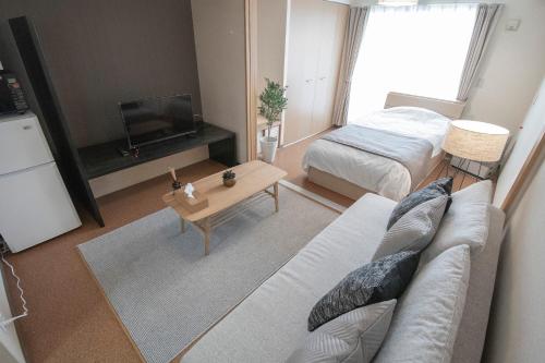 a living room with a couch and a tv and a bed at UCHI Living Stay Otaru Suitengu in Otaru