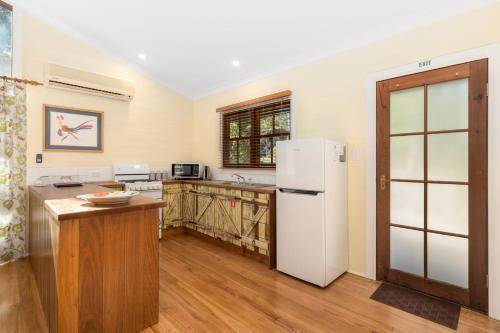 a kitchen with a white refrigerator and a table at Friday Creek Retreat in Coffs Harbour