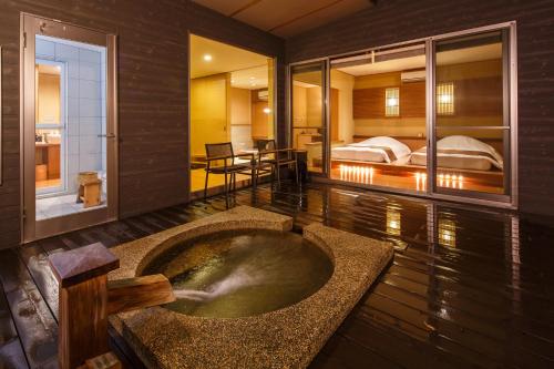 a room with a tub in the middle of a room with two beds at Okuyado Buaiso in Yufuin
