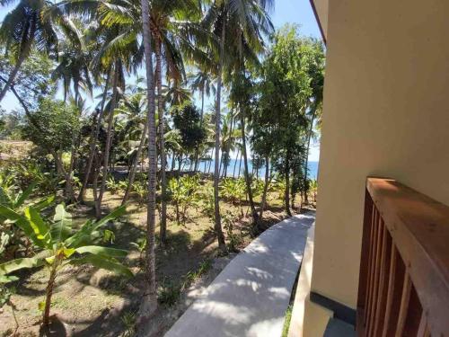a balcony with a view of the beach and palm trees at Bahari Villa Tejakula in Tejakula