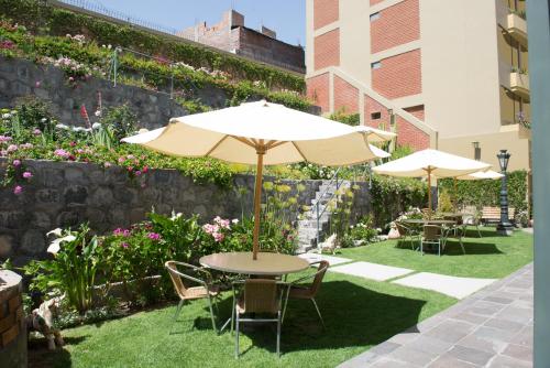 a table and chairs with an umbrella in a garden at El Cabildo Hotel in Arequipa