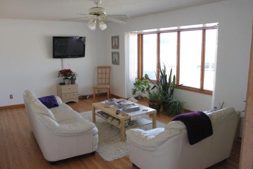 a living room with two white chairs and a table at The Inn on College in Saskatoon