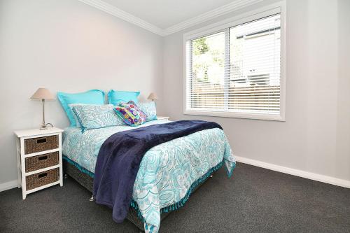 a white bedroom with a bed and a window at The Weiti Waterfront in Whangaparaoa