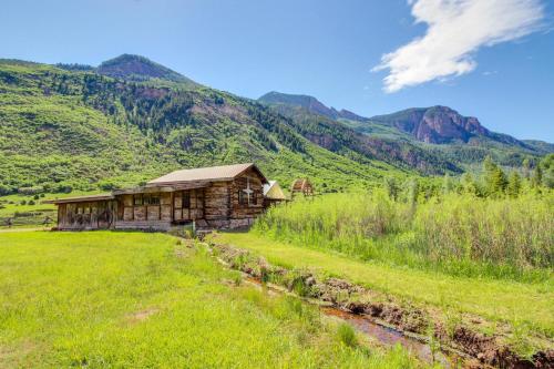 a log cabin in a field with mountains in the background at Chair Mountain Cabin at Filoha Meadows in Redstone