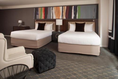 a hotel room with two beds and a chair at The Fifty Sonesta Hotel New York in New York