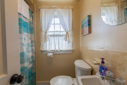 a bathroom with a toilet and a sink and a window at The Eastern Avenue Cottage in Wells Beach