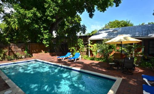 a swimming pool with two chairs and an umbrella at Key Lime Calypso in Key West